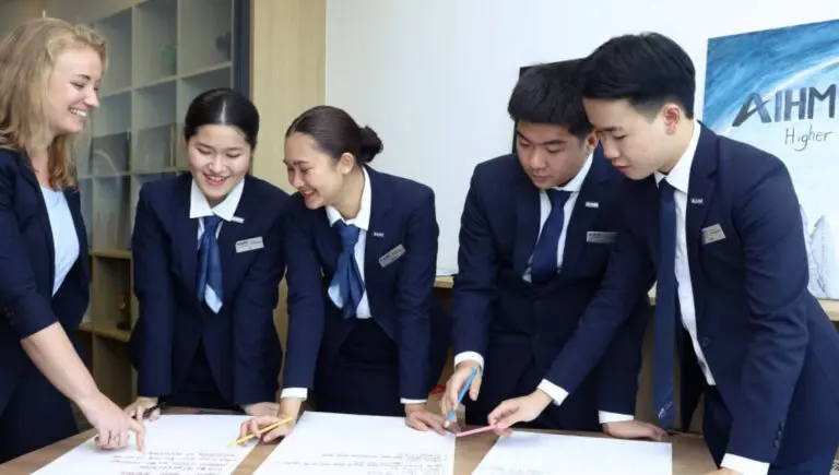 AIHM hospitality students collaborate with an international lecturer during a classroom workshop, developing teamwork, communication, and problem solving skills.