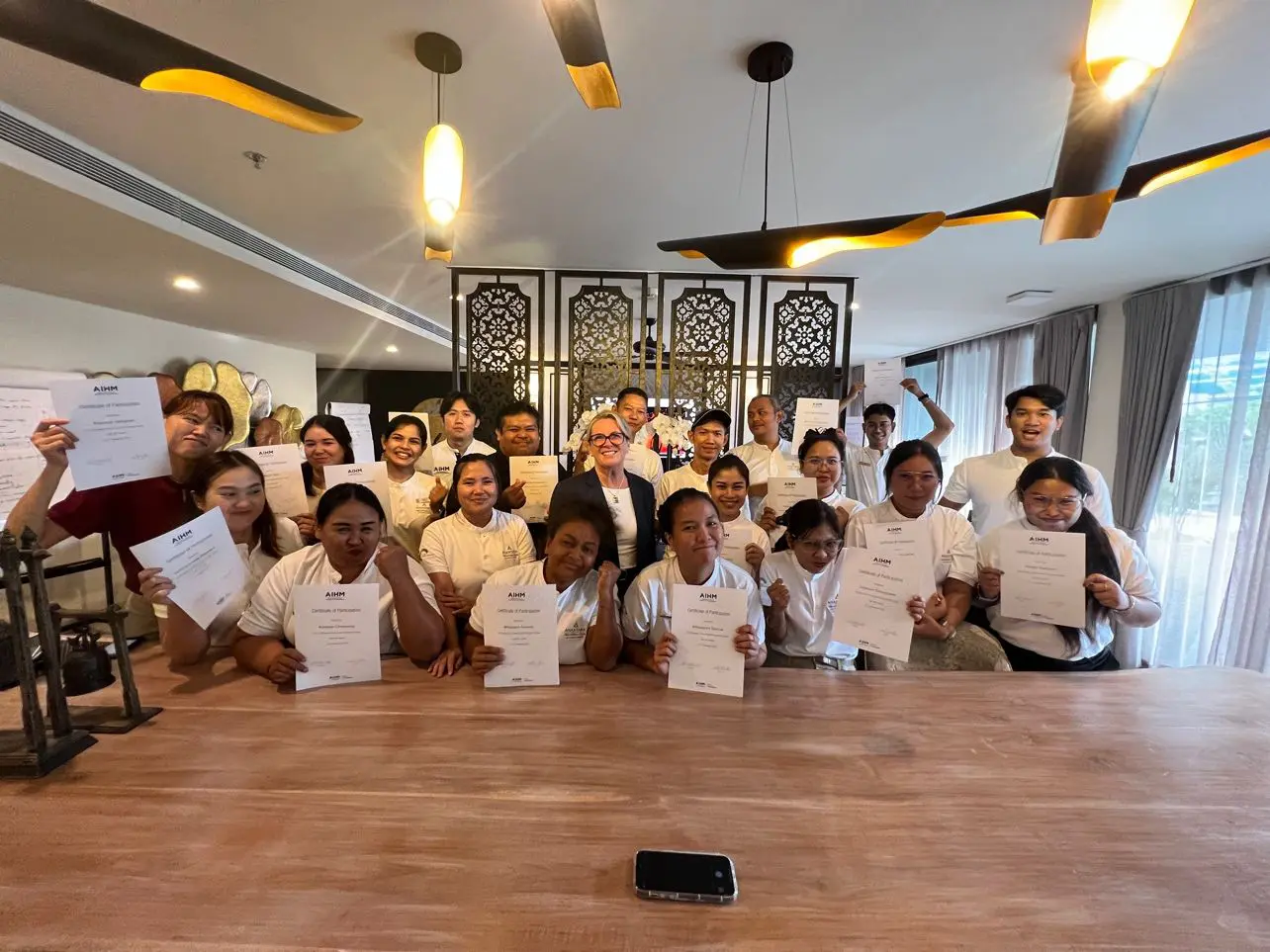 AIHM custom training graduates proudly holding certificates after an emotional intelligence and service excellence workshop, celebrating team development, upskilling, and hospitality training success.
