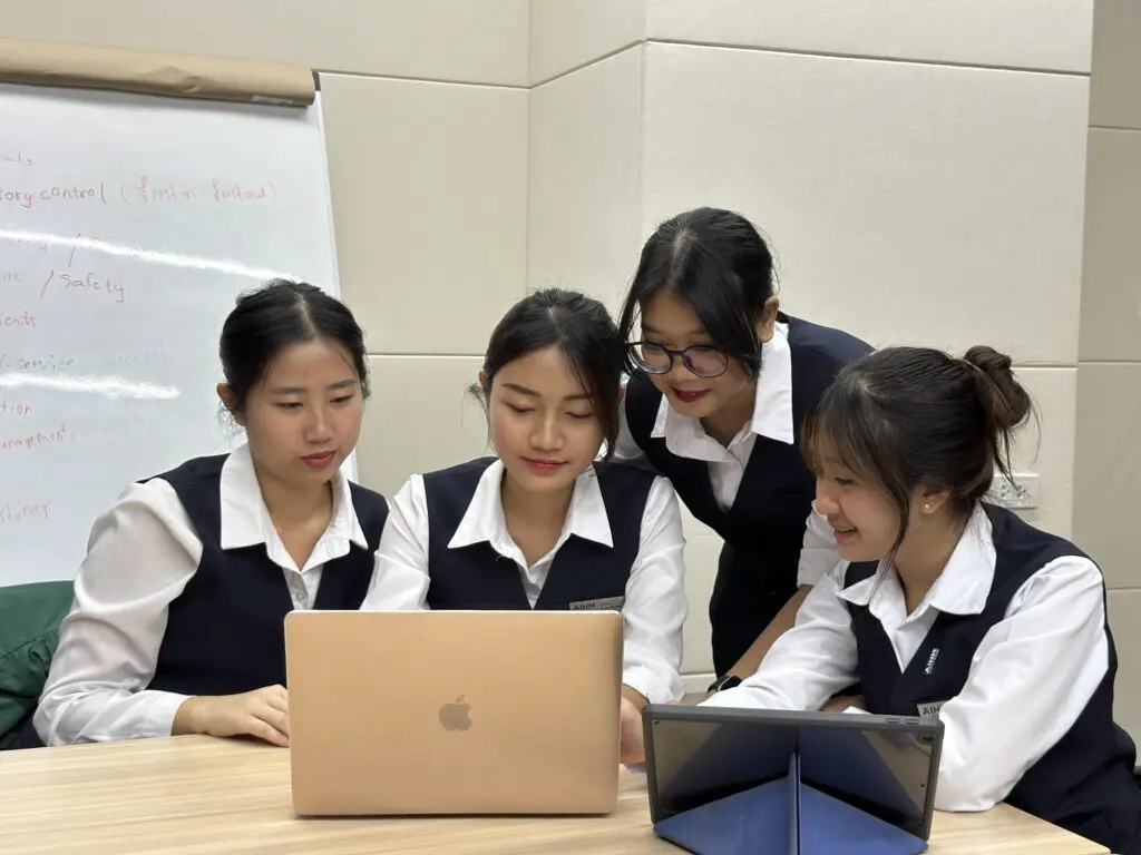 AIHM students collaborating with laptops during the BTEC Higher National Diploma in Business & Marketing, building real-world marketing, management, and analytical skills.