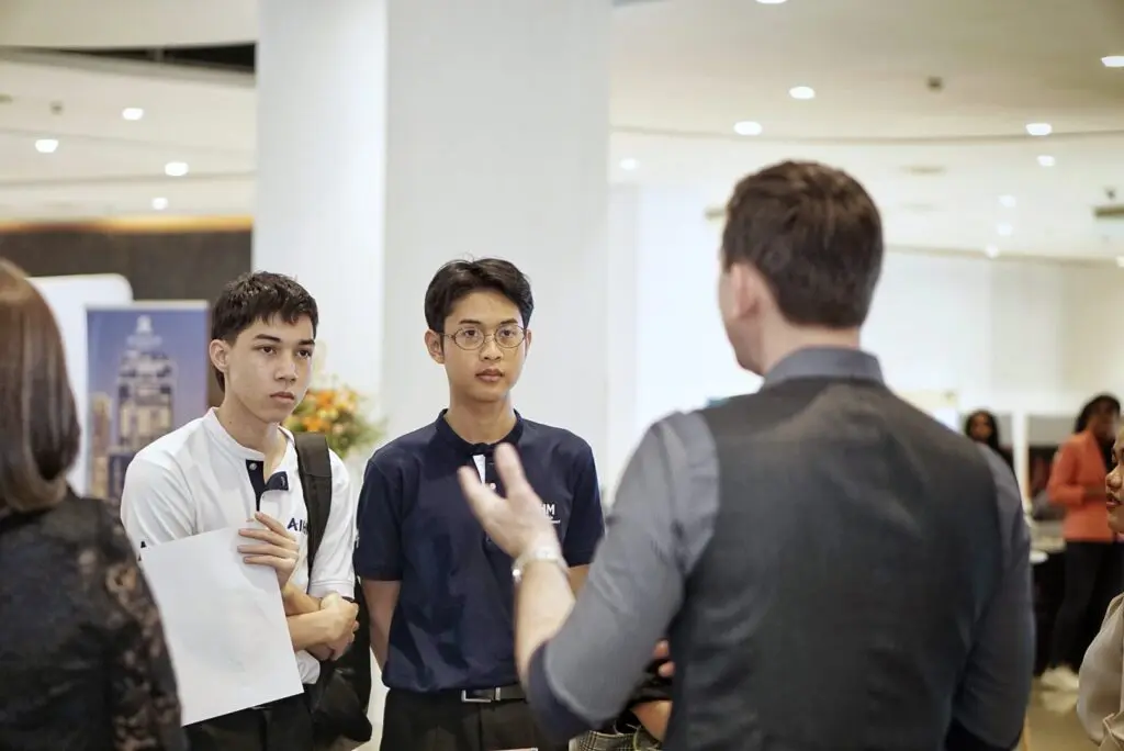 AIHM student ambassadors engage with an industry professional at a hospitality career event, showcasing hospitality management education, career guidance and global pathways in Bangkok.
