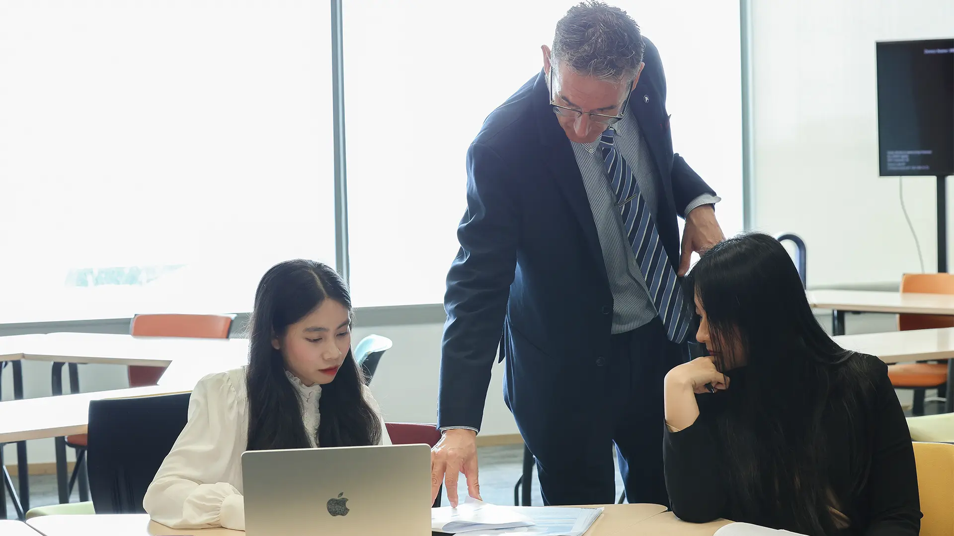 AIHM lecturer mentoring postgraduate students during hospitality management coursework at AIHM Bangkok as part of the Postgraduate Diploma in International Hospitality Management programme.