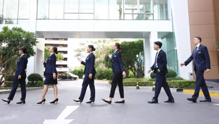 Hospitality management students walking confidently across the AIHM campus in professional uniforms, representing hands on learning and future hospitality leadership in Bangkok.