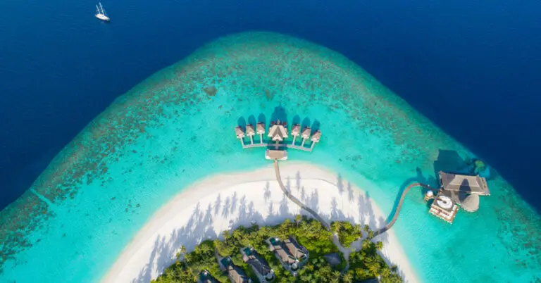 Aerial view of a Maldives island resort with overwater villas and turquoise lagoon, illustrating AIHM hospitality scholarship opportunities for Maldivians