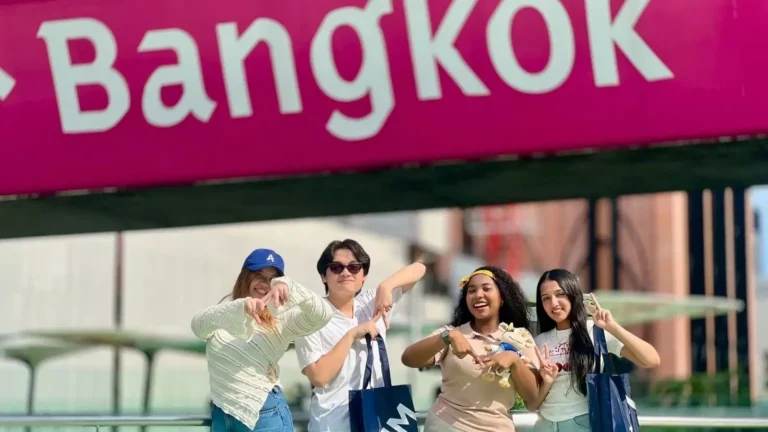 International students posing in front of a Bangkok BTS sign while studying hospitality education in Thailand at AIHM