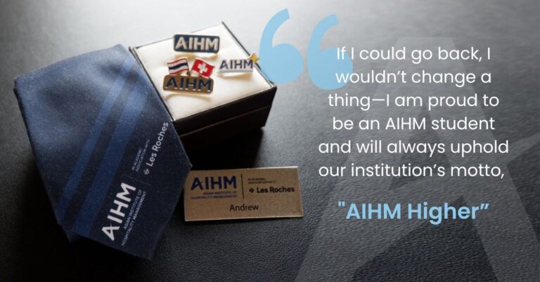 A blue Les Roches tie and AIHM pins on a box, with a name tag reading "Andrew." A quote praises being an AIHM student, highlighting pride and the motto, "AIHM Higher."