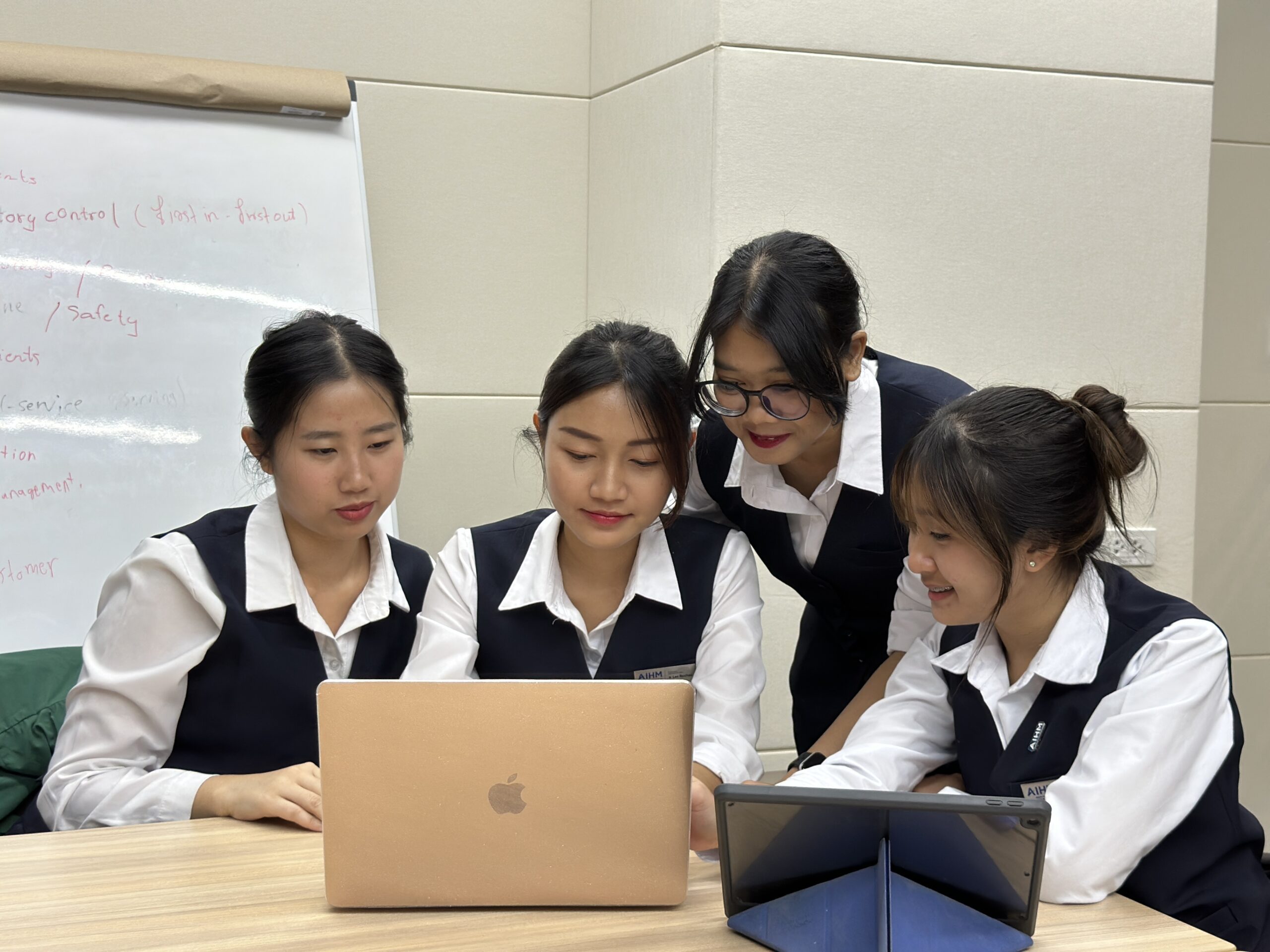 AIHM students collaborating with laptops during the BTEC Higher National Diploma in Business & Marketing, building real-world marketing, management, and analytical skills.