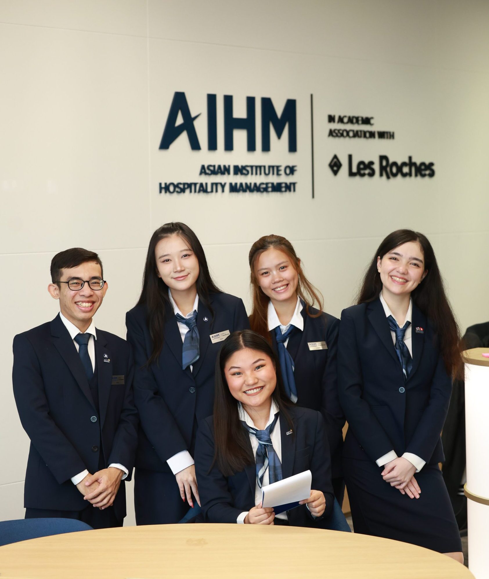 AIHM hospitality management students in formal uniforms standing together at the AIHM campus, representing the BBA in Global Hospitality Management in academic association with Les Roches.