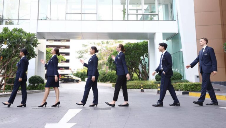 Hospitality management students walking confidently across the AIHM campus in professional uniforms, representing hands on learning and future hospitality leadership in Bangkok.