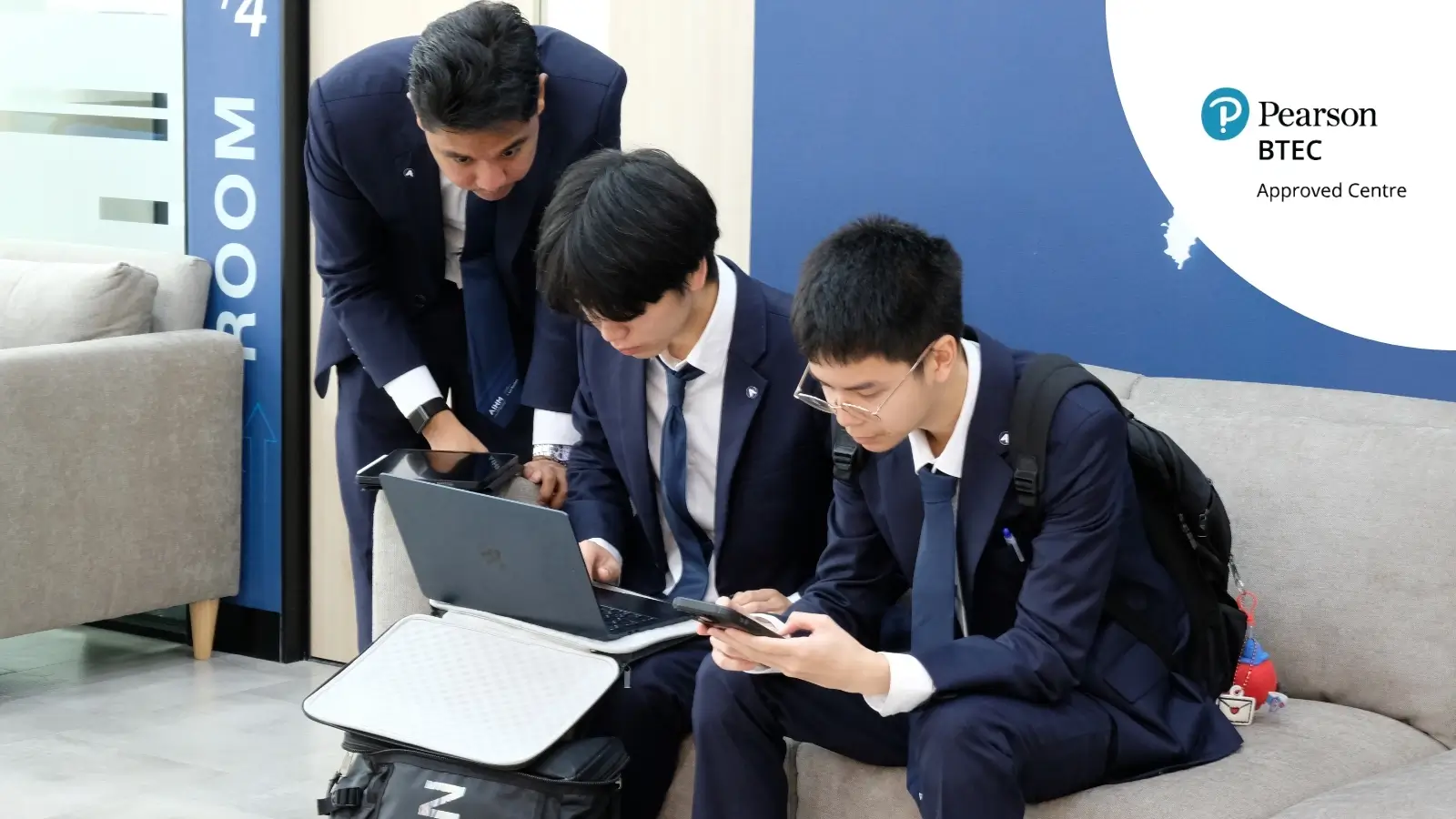 AIHM BTEC students studying business and IT pathway in Bangkok, collaborating on laptops and digital tools in a modern learning environment