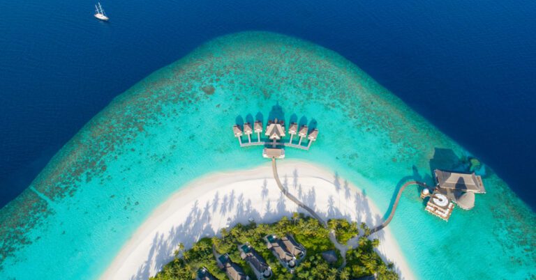 Aerial view of a Maldives island resort with overwater villas and turquoise lagoon, illustrating AIHM hospitality scholarship opportunities for Maldivians