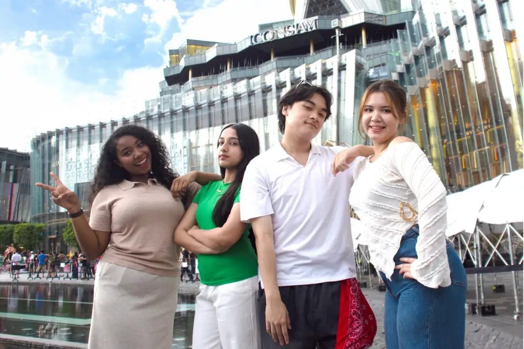Group of four AIHM students posing outdoors in front of ICONSIAM, a shopping and lifestyle destination near AIHM campus