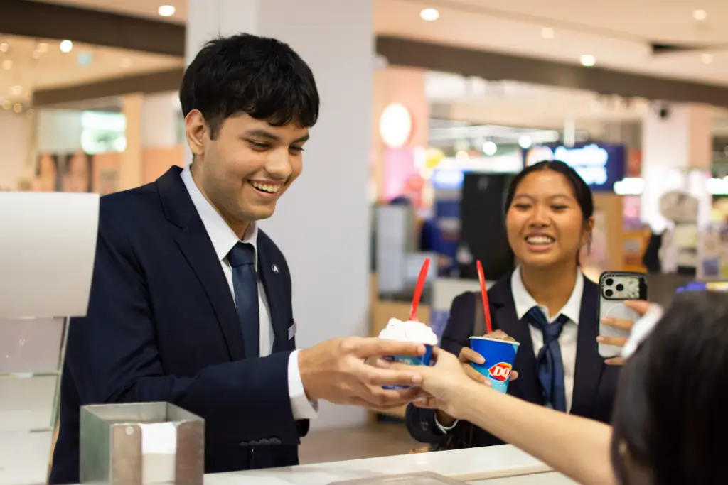 AIHM students in uniform smiling and enjoying ice cream together at Riverside Plaza after a day of study