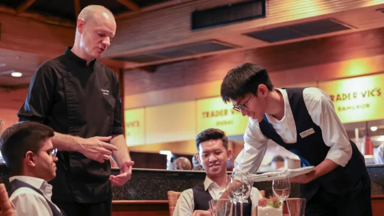 AIHM lecturer coaches a student on table service technique.